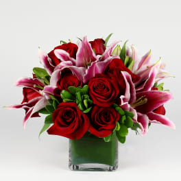 Red roses and pink lilies in a square glass vase