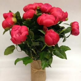 Pink peony arrangement in a glass vase wrapped with burlap and twine