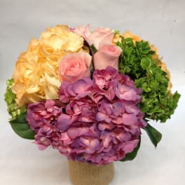 Bouquet of pink roses and hydrangeas in a burlap-wrapped container