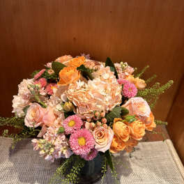 Peach and pink mixed flower arrangement in a dark vase