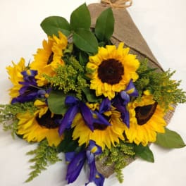 Bouquet of sunflowers and purple irises wrapped in burlap