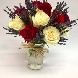 Red and cream roses with purple lavender in a glass jar vase