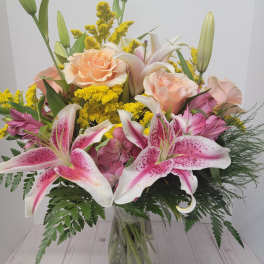 Bouquet of pink lilies and peach roses in a glass vase