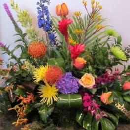 Large colorful floral arrangement with mixed blooms and tropical foliage