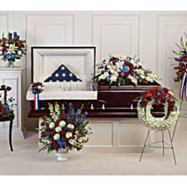 Sympathy floral tribute with red, white, and blue arrangements around a casket
