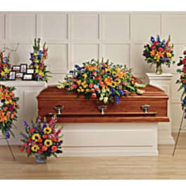 Colorful funeral floral sprays around a casket in a chapel