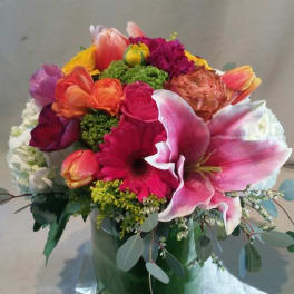 Colorful mixed bouquet in a glass vase with a large pink lily