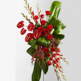 Red roses and anthuriums with tall green leaves in a modern arrangement