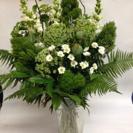 Tall green bouquet with white daisies in a clear glass vase