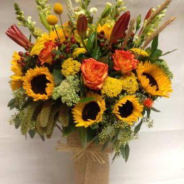 Sunflower and rose arrangement in a burlap-wrapped vase