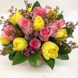 Bouquet of pink roses and yellow tulips in a glass vase
