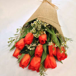 Bouquet of red tulips wrapped in burlap with small white filler flowers