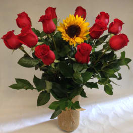 Bouquet of red roses and a sunflower in a burlap-wrapped vase