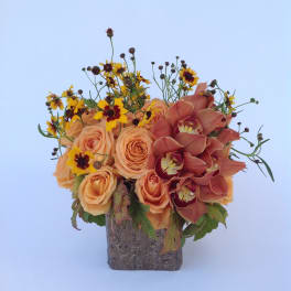Peach roses and burgundy orchids in a square vase