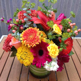 Colorful mixed bouquet in a green glass vase with roses and daisies