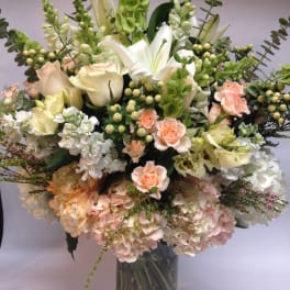 Tall bouquet of white and peach flowers in a glass vase