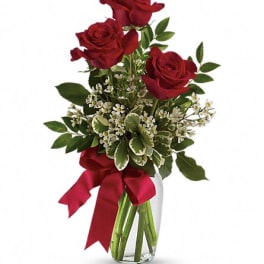 Red roses in a clear glass vase with a red ribbon