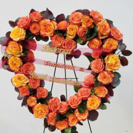 Heart-shaped rose wreath on a stand with pink ribbons