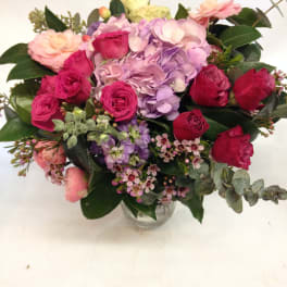 Mixed pink, purple, and red roses in a clear glass vase