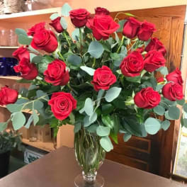 Bouquet of red roses in a clear glass vase with eucalyptus