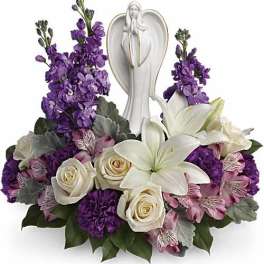 Purple and white floral arrangement with an angel figurine centerpiece