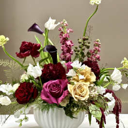 Mixed bouquet of roses, calla lilies, and white blooms in a white vase