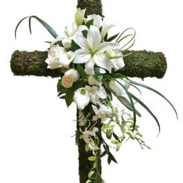 White flowers arranged on a moss-covered cross