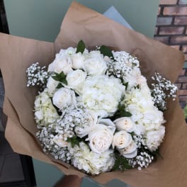 White rose and hydrangea bouquet wrapped in brown paper