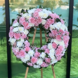 Pink and white carnation wreath on a wooden stand