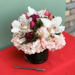 Pink and white floral arrangement in a black vase