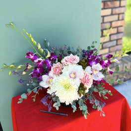 Pink roses and white orchids arranged with a large white chrysanthemum in a low vase