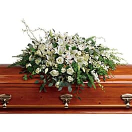 White floral casket spray on a wooden coffin