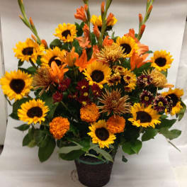 Mixed bouquet of sunflowers and orange flowers in a dark basket