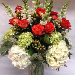 Red roses and white hydrangeas in a clear glass vase
