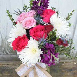 Bouquet of pink and red roses with white daisy-like blooms in a vase
