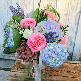 Bouquet of pink roses and blue hydrangeas in a glass vase