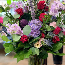Bouquet of red roses and lavender flowers in a glass vase