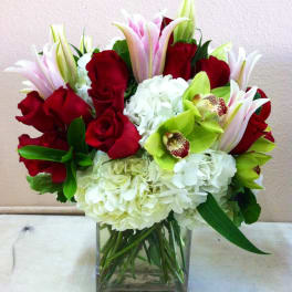 Bouquet of red roses, white hydrangeas, and green orchids in a glass vase