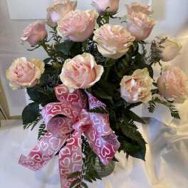 Bouquet of pale pink roses with a pink heart ribbon in a glass vase