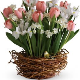 Pink tulips and white flowers arranged in a woven basket