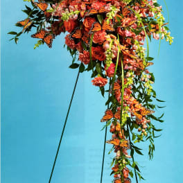 Orange floral standing spray with butterflies on a metal easel