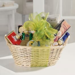 Gift basket with chocolates, cookies, and a bottle tied with a green ribbon