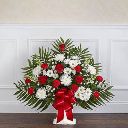 Standing floral spray with red roses, white daisies, and a red bow
