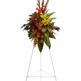 Tall floral standing spray with red, orange, and yellow blooms on an easel