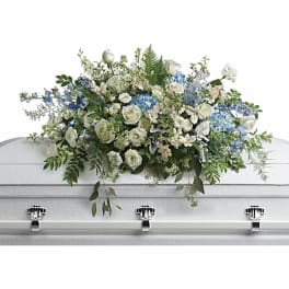 White and blue floral casket spray on a white coffin