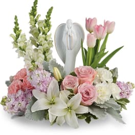 Pastel floral arrangement with roses, lilies, tulips, and an angel figurine