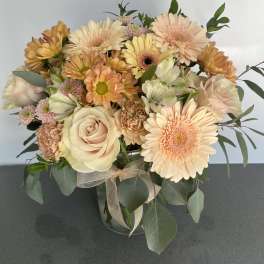Peach and cream bouquet of roses, gerbera daisies, and carnations in a glass vase