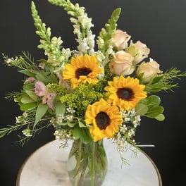 Sunflowers and pale roses in a glass vase