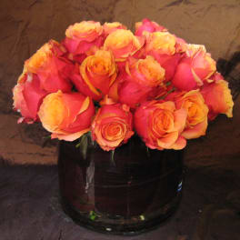 Pink and orange roses arranged in a dark glass vase