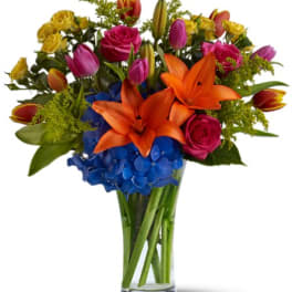 Colorful bouquet of lilies, roses, tulips, and hydrangeas in a glass vase